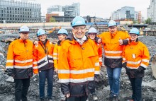 Direktør Harald Nikolaisen i Statsbygg med noen av de viktigste arbeidsgiverprofilerne i virksomheten - de ansatte. Mann i byggeklær omkranset av kolleger